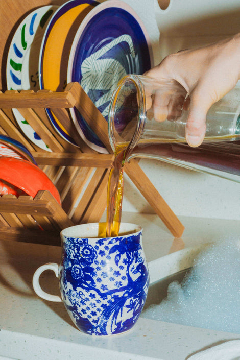 Photo of a hand pouring coffee into a mug from a carafe.